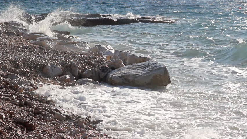 Waves splashing the beach, people sunbathe and enjoy on vacation, island Brac in Croatia