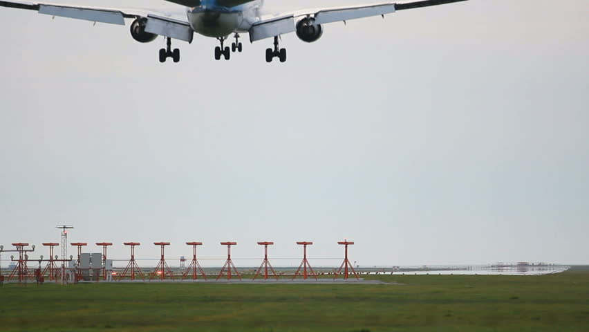 Commercial Jet Plane landing. A jet airplane. Landing gear down, runway markers in the foreground.
