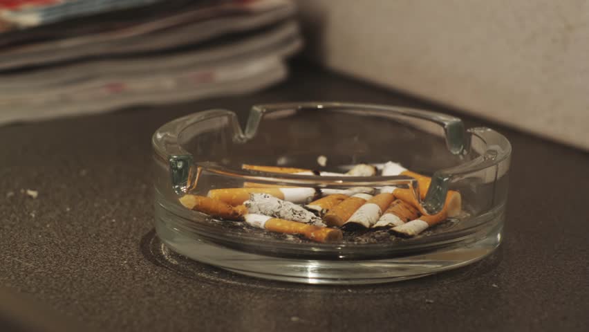 Man's putting out a cigarette in ashtray.