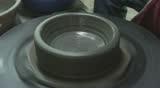 Two hands are molding clay into a vase.