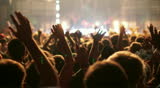 Shot of some cheering fans at a life concert, slow motion, some visible noise due high ISO, soft focus
