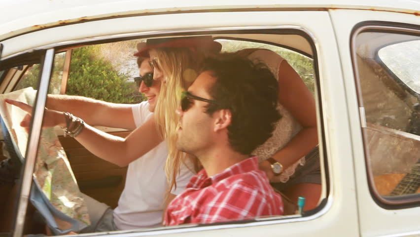 Young Hipster friends on a roadtrip looking at a map.
