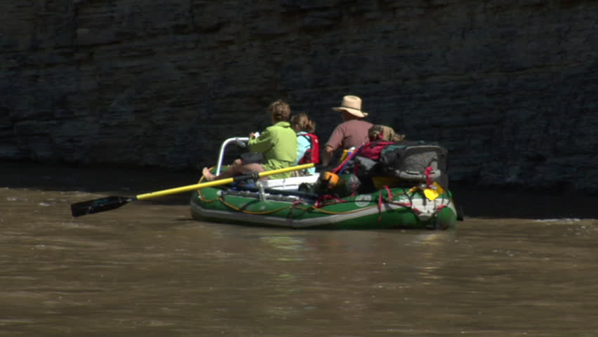 Family on river raft in rocky canyon