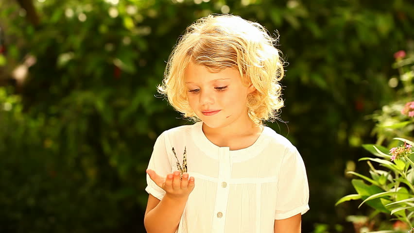 Young girl in nature holding a rice paper butterfly until it takes off, circles her and makes her smile. 