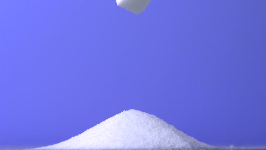 Sugar cubes falling down into pile of sugar on purple background in slow motion