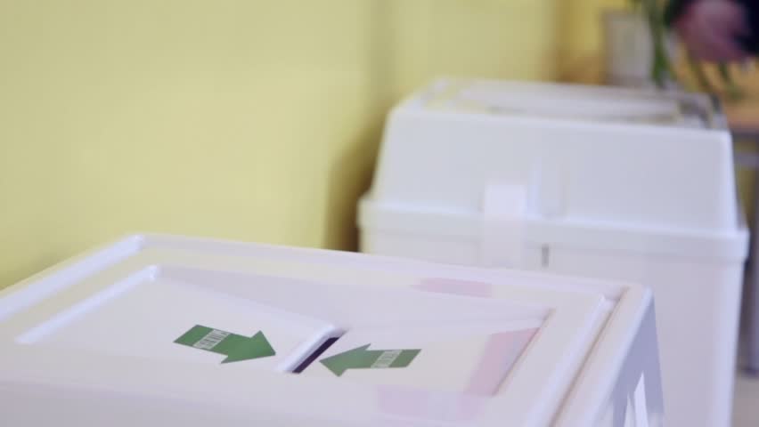 Hands of people drop ballots in box with Bulletin inscription during voting, closeup