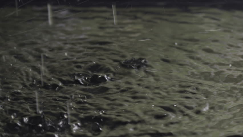 Water drops in slow motion, rain on lake with reflection of stormy sky