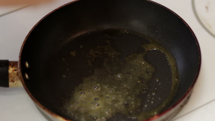 Egg drops into hot pan, frying the egg and denaturing proteins.
