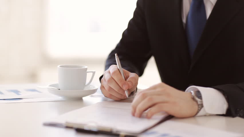 man in suit and tie signing a contract