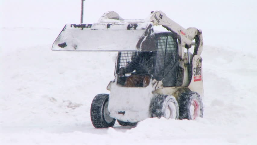Man plowing snow in parking lot. 