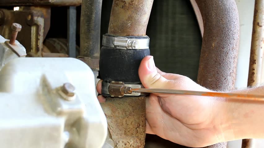 Two Hose Clamps On An Old Diesel Engine Adjusted With A Flat Tip Screwdriver