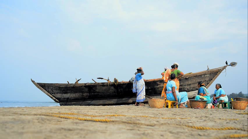 MORJIM, GOA, INDIA - MARCH 11: Indian women sorted fresh caught fish for sale on a beach near fisher boat, Morjim, March 11, 2013 in Goa India. This activity will provide a income stream for people.