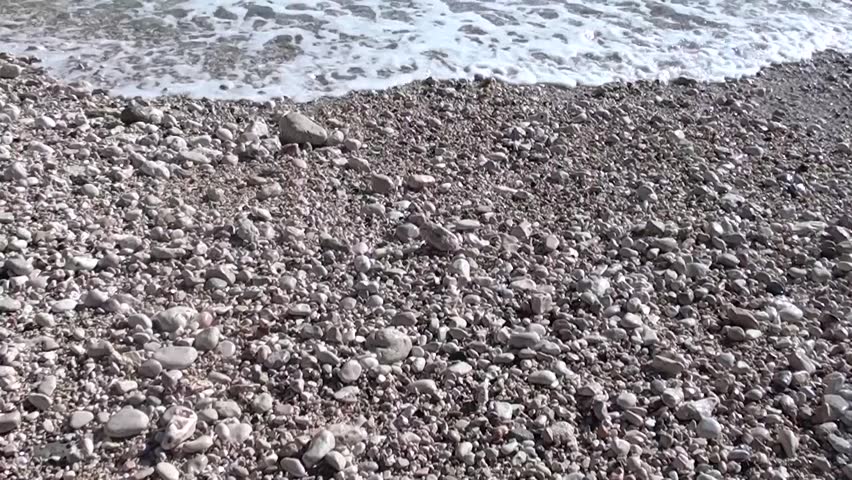 Sea is washing pebbles on the bay beach, tilt