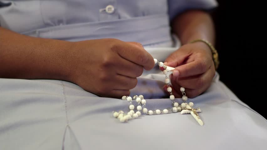 People, nun and religion, catholic sister praying in church and holding cross, holy rosary in hands. With model release