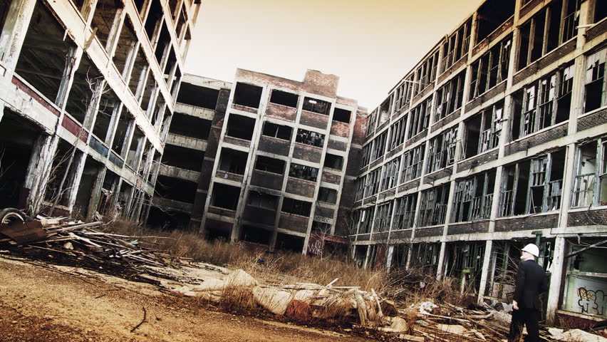 Developer walks into shot and looks around at the ruined buildings around him, making notes. Wide shot with strong rust tones, high-contrast and dramatic filtration.