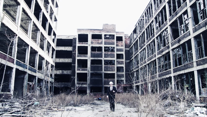 Developer walks into shot and looks around at the ruined buildings around him, making notes. Wide shot with cold blue tones, high-contrast and dramatic filtration.