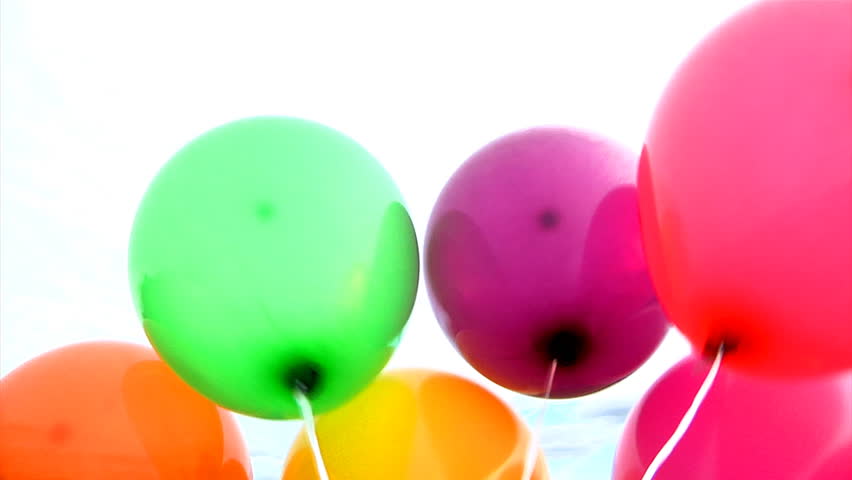 A bunch of colorful helium balloons fly off into the sky