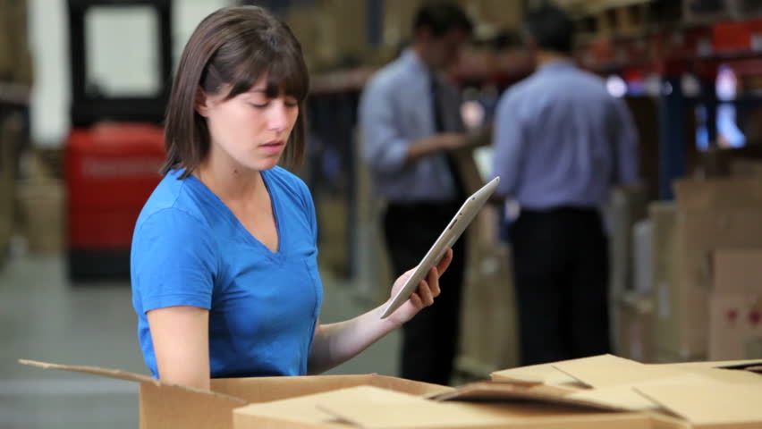 Female worker checks contents of boxes using digital tablet. Shot on Canon 5d Mk2 with a frame rate of 30fps