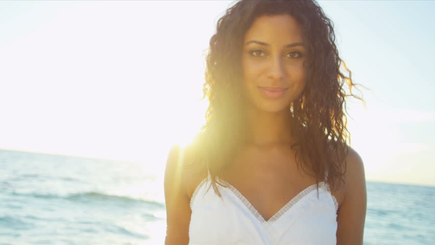 Happy Latin American girl smiling to camera enjoying beach at sunset sun lens flare shot on RED EPIC