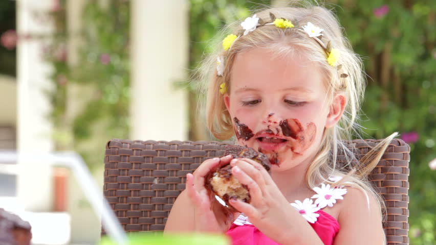 Girl sitting at table eating large messy slice of chocolate cake. Shot on Canon 5d Mk2 with a frame rate of 30fps