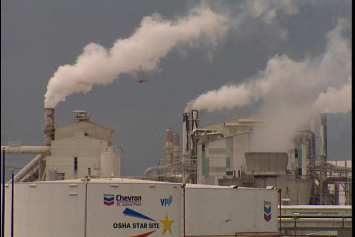 CONVENT, LOUISIANA - CIRCA SEPTEMBER 1999: Chevron oil storage tank with smokestacks behind spewing smoke.
