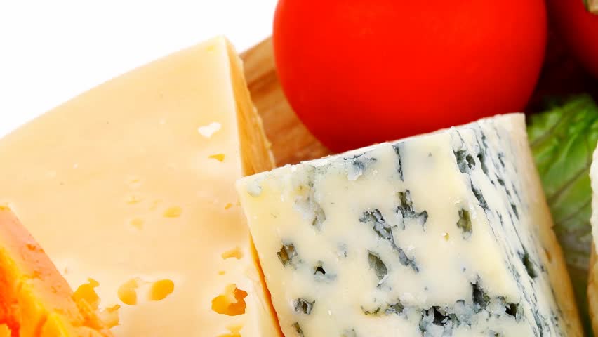 soft feta cheese with aged delicatessen cheeses on cutting wooden plate with tomatoes bread and olive oil