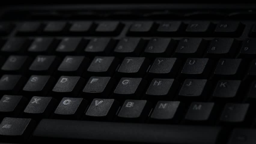 Internet Security Concept for Identity Theft. A Flashlight passing over a Keyboard in the Dark.