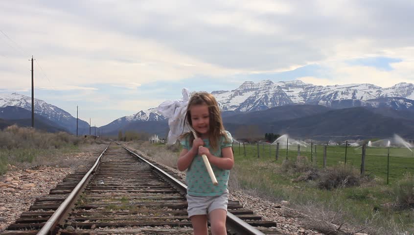 Little girl alone, walking down the railroad tracks.
