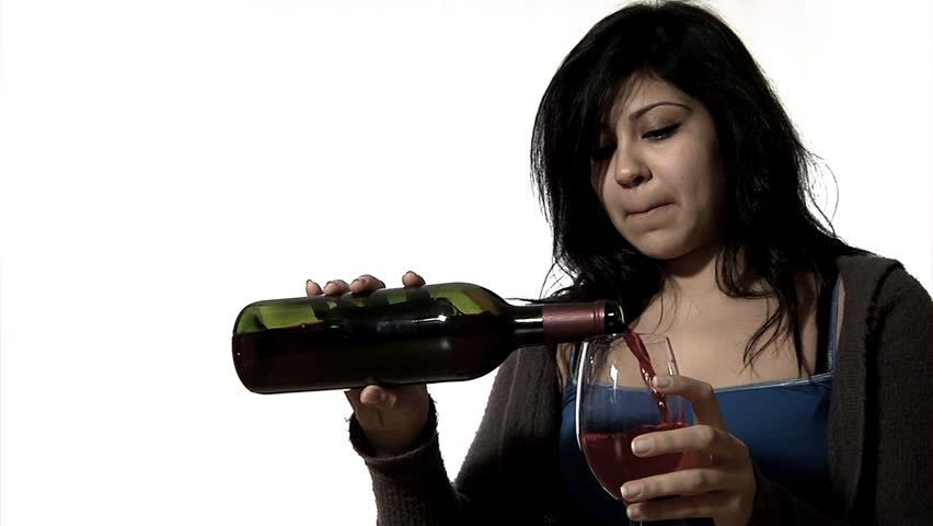 Woman drowning her sorrows - a young woman drinks a whole bottle of red wine alone - desaturated