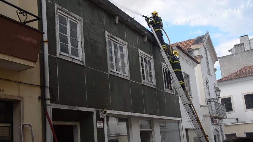 Rio Maior , Portugal - 03 May 2013 Local firefighters fight to extinguish this urban fire on the roof of a cloth shop. 