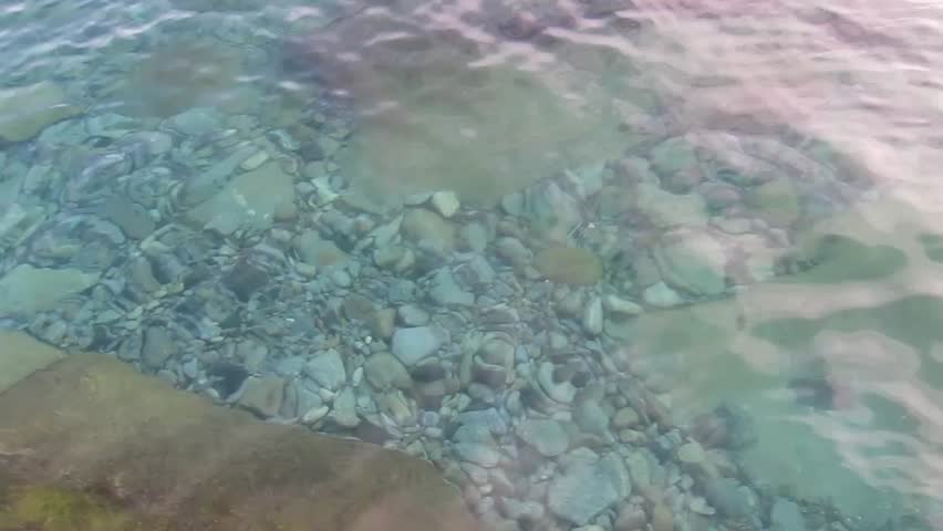 light blue water from the Mediterranean sea, with pebbles and rocks, from a beautiful beach in the island of Elba in Tuscany, Italy