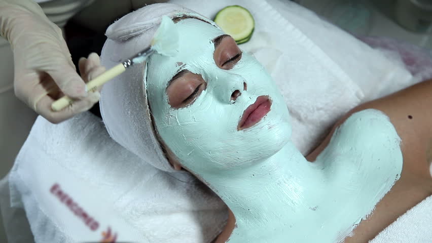 Woman taking facial mask and enjoying it in spa salon