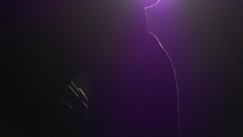 Man in silhouette talks on mobile phone on a cold winters night, the camera jibs up past him to the light