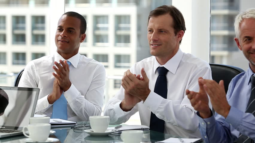 Business people clapping sitting in board room after presentation