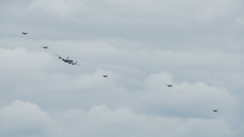 Avro Lancaster bomber flying in formation with RAF Spitfires and Hurricanes from World War II.