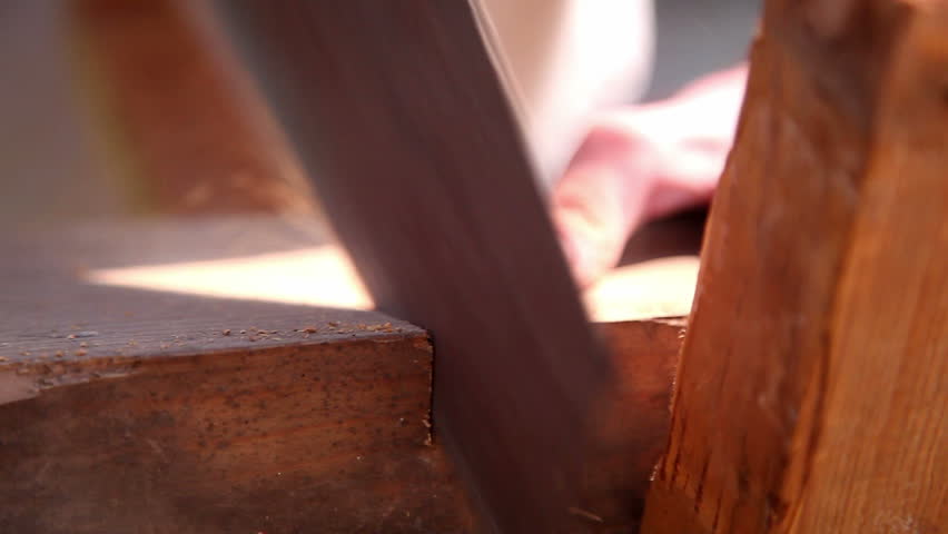 man cuts wood with saw
