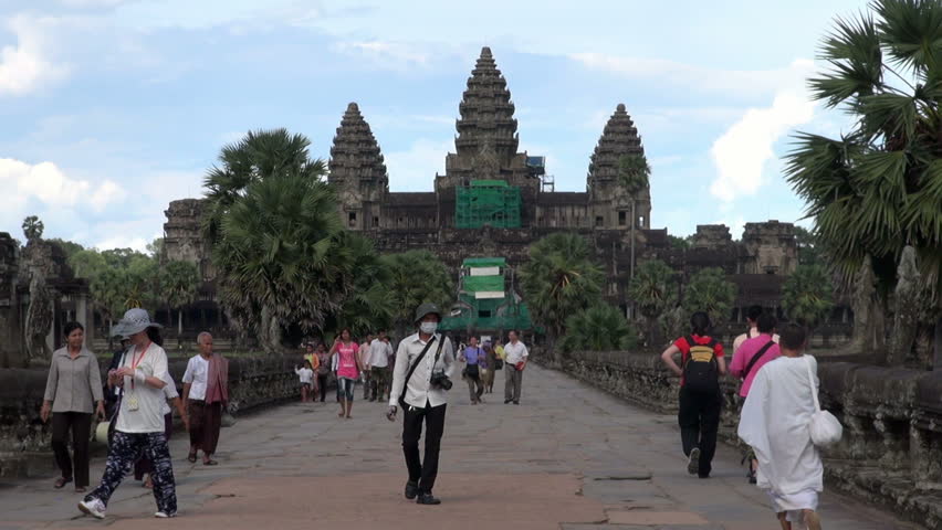SIEM REAP, CAMBODIA - CIRCA JUNE 2011 - Tourists who visit Angkor Wat Temple walk at the main entrance.  