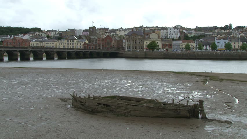 A small wooden boat sunk and rotting in the estuary of the river Torridge at Bideford.