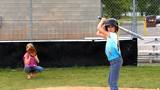 A young girl hits a slow pitch from her sister.