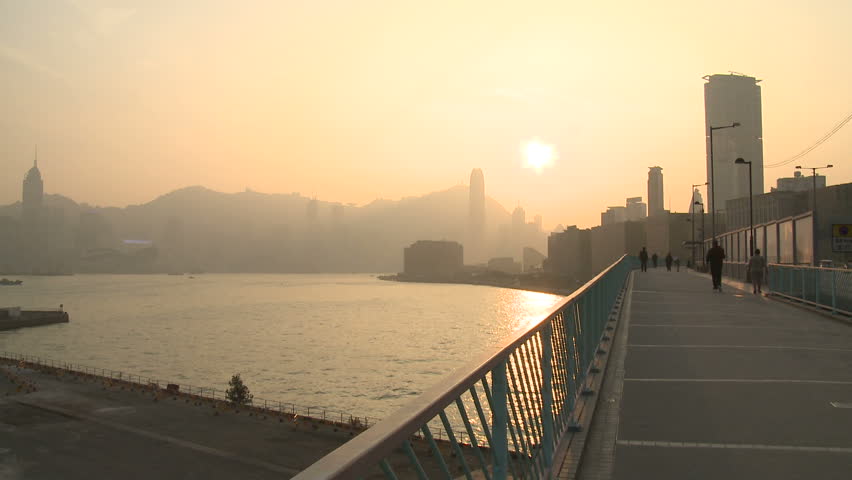 HONG KONG, CHINA - FEBRUARY 2012: Air pollution and choking smog cloak the skyline of Hong Kong as pedestrians walk on bridge at sunset. Shot in full HD 1920x1080 30p on Sony EX1.
