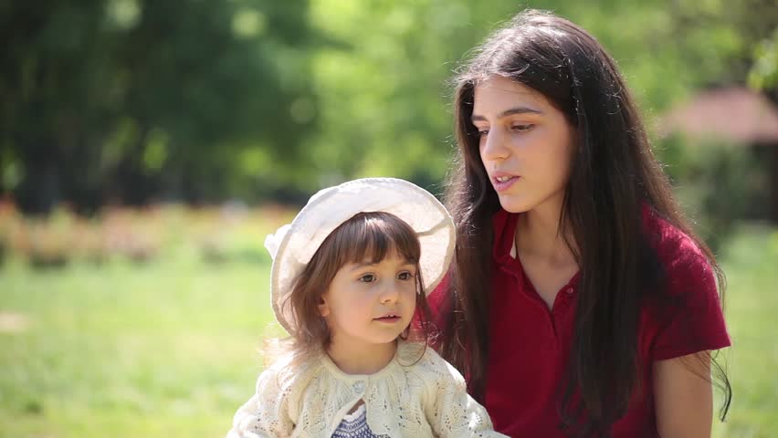 Young adult mother and daughter sing and hug together.
