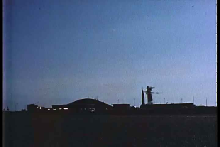 1960s - Military vehicles passing at dawn at a base.