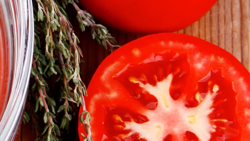cold fresh diet tomato soup with basil thyme and raw tomatoes in transparent bowl over red mat on wood table ready to eat 1920x1080 intro motion slow hidef hd