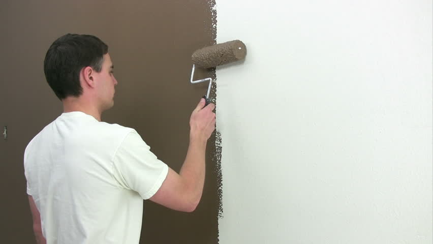 Man painting on a wall with a roller