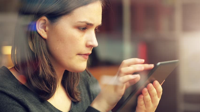 woman using tablet computer touchscreen in cafe drinking coffee