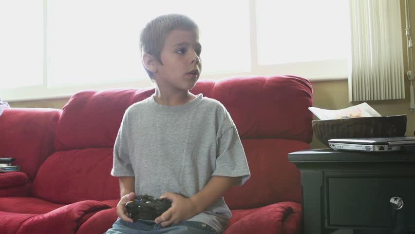 Young boy jumps onto couch while playing game