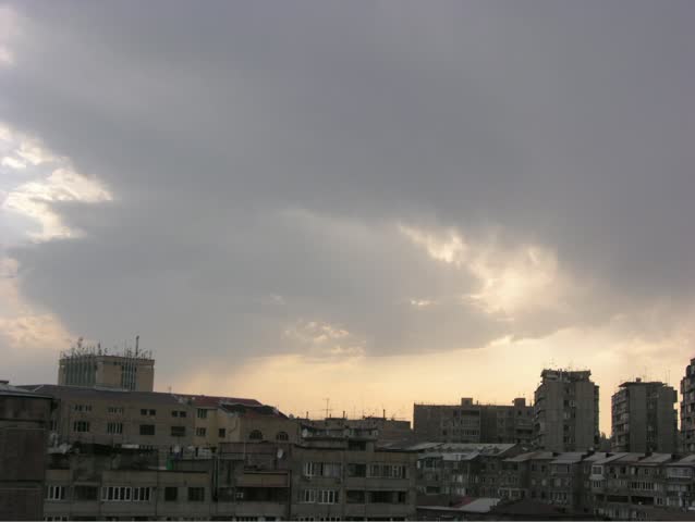 Sunset and moving clouds over city buildings. Time lapse