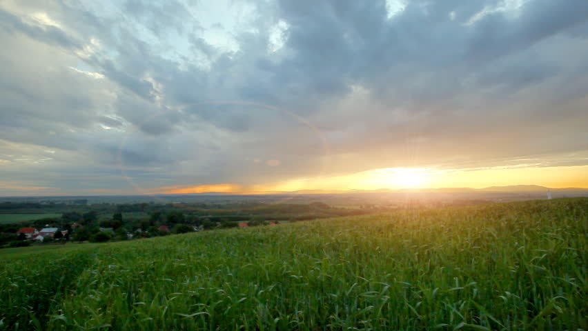 Time lapse ?? moving clouds at sunset over green grass 