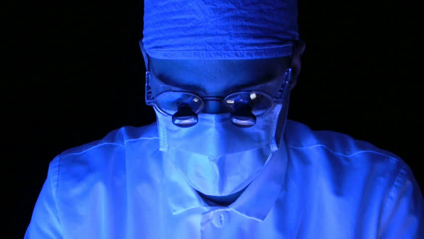 Straight on shot of a surgeon working, blue light.  HD 1080i