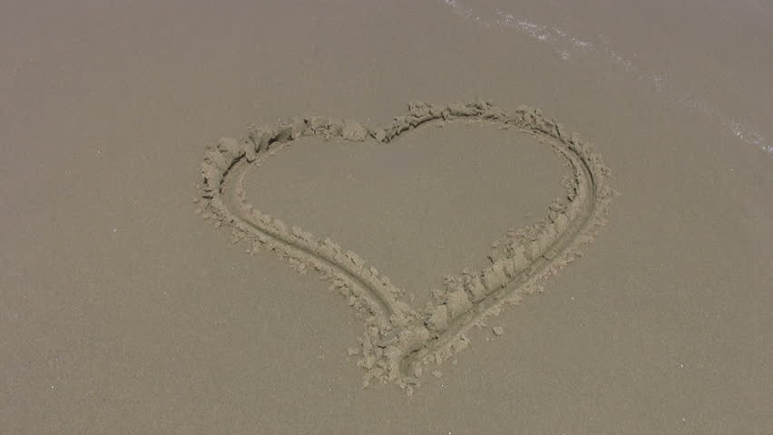 Video of a heart written or scratched in the sand of beach. Waves washing the heart away. Gulf of Mexico. Clean sand. Don Despain of Rekindle Photo